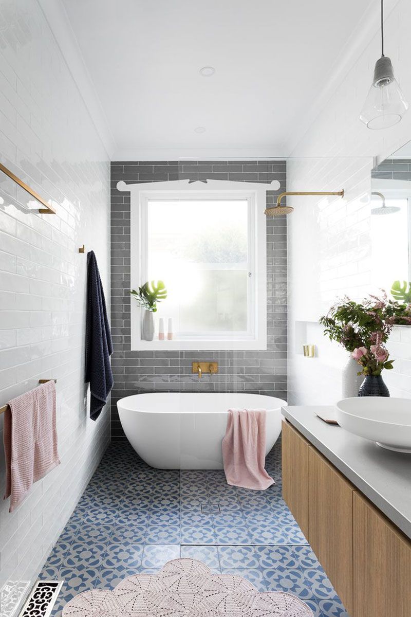 Просторная светлая ванная с нежными оттенками розового цвета и синей плиткой на полу
