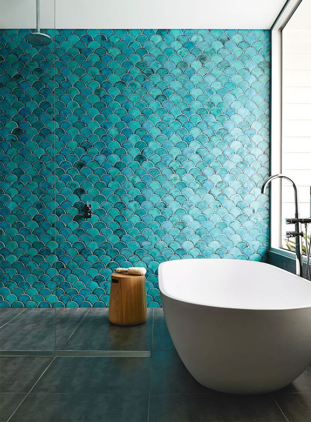 Минималистический дизайн ванной комнаты поддержан с помощью чешуйчатой плитки цвета лазури во всю стену