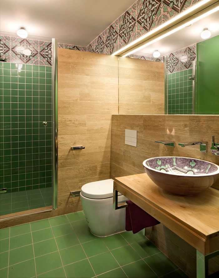 Зеленая плитка на стенах душевой и на полу стала фоновой для роскошных керамических бордюров, расположенных под самым потолком