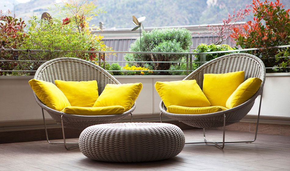 Мебель из ротанга с яркими подушками — украшение совмещенного с кухней балкона