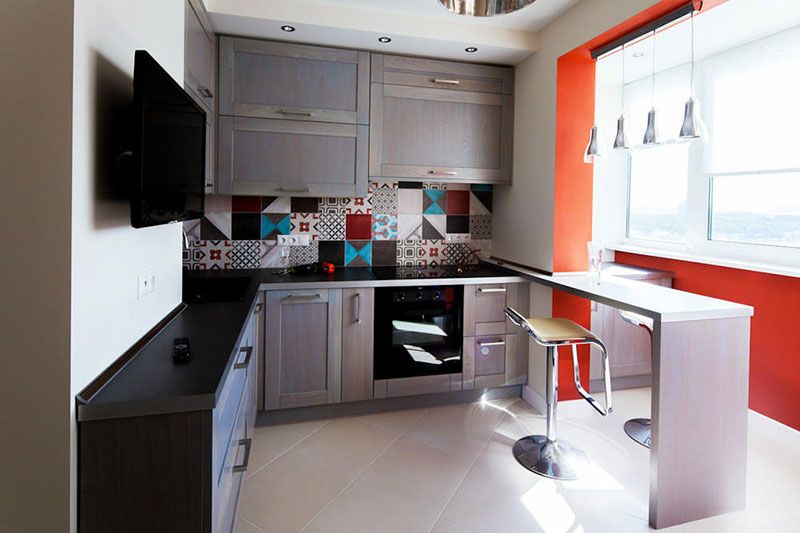 Контраст серой кухни и небольшого балкона в оранжевом цвете