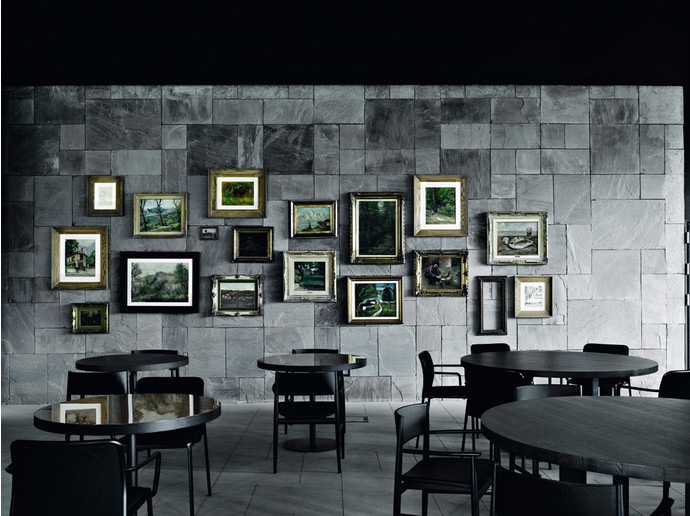 Картины в классических позолоченных рамах эффектно смотрятся на фоне стены из серого камня. Кресла, Porro.